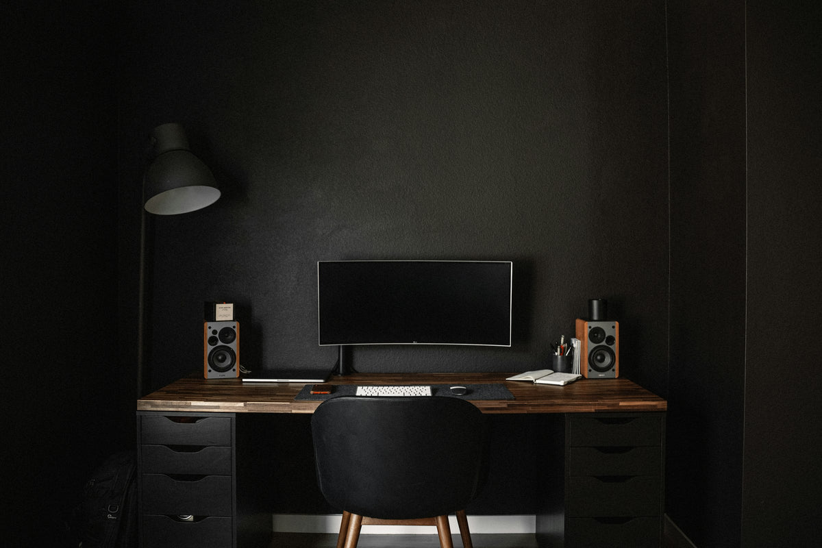 Dark minimal desk setup with a monitor and lamp